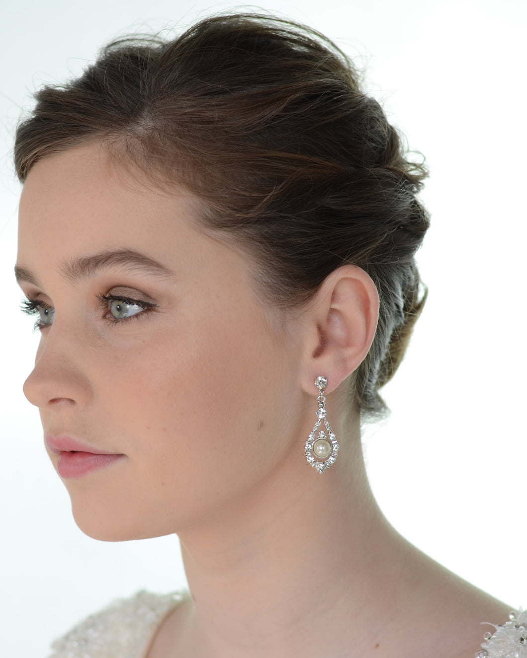 Close-up of a woman wearing a diamond earring on a white background
