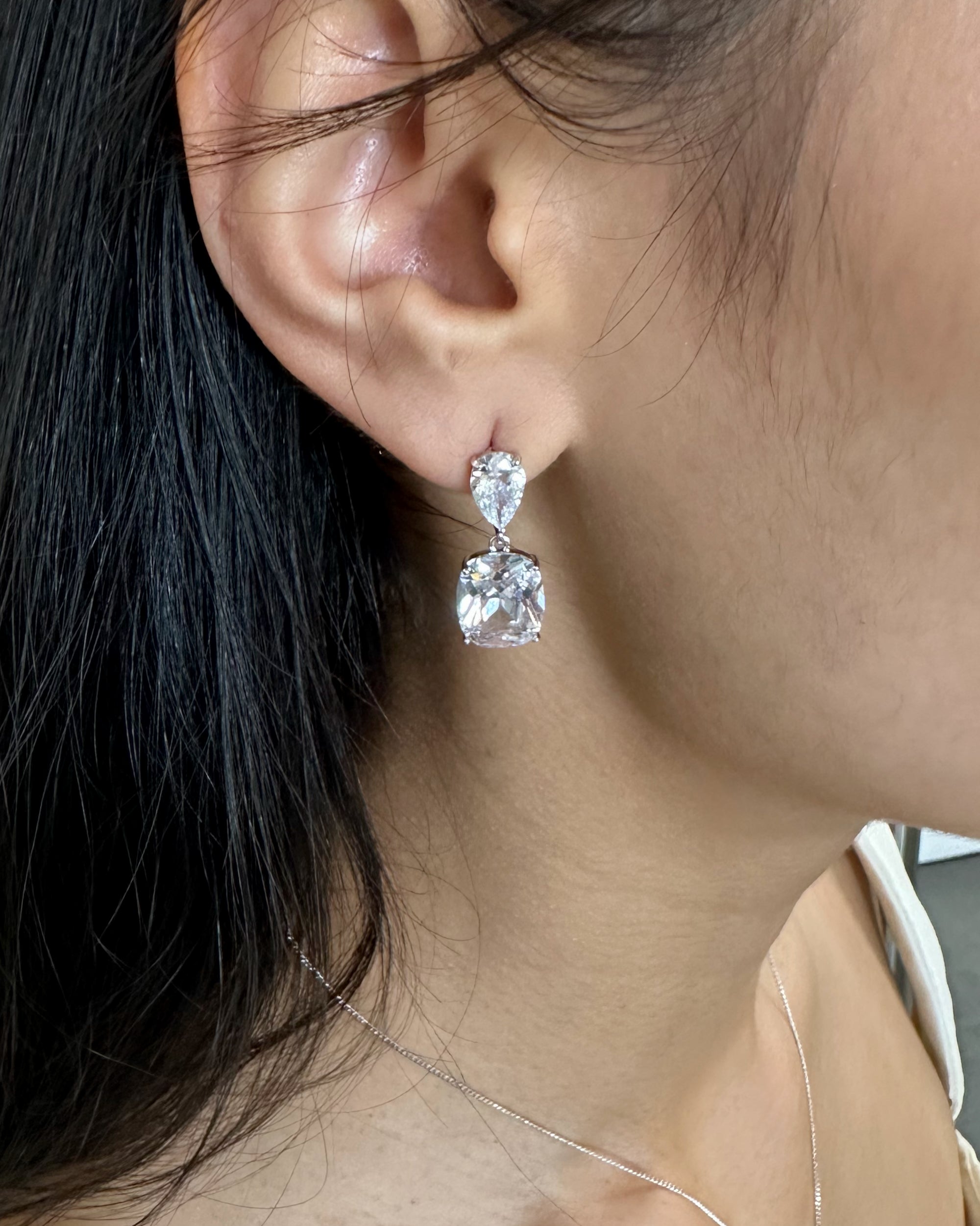 Close-up of a person wearing a pair of diamond earrings.