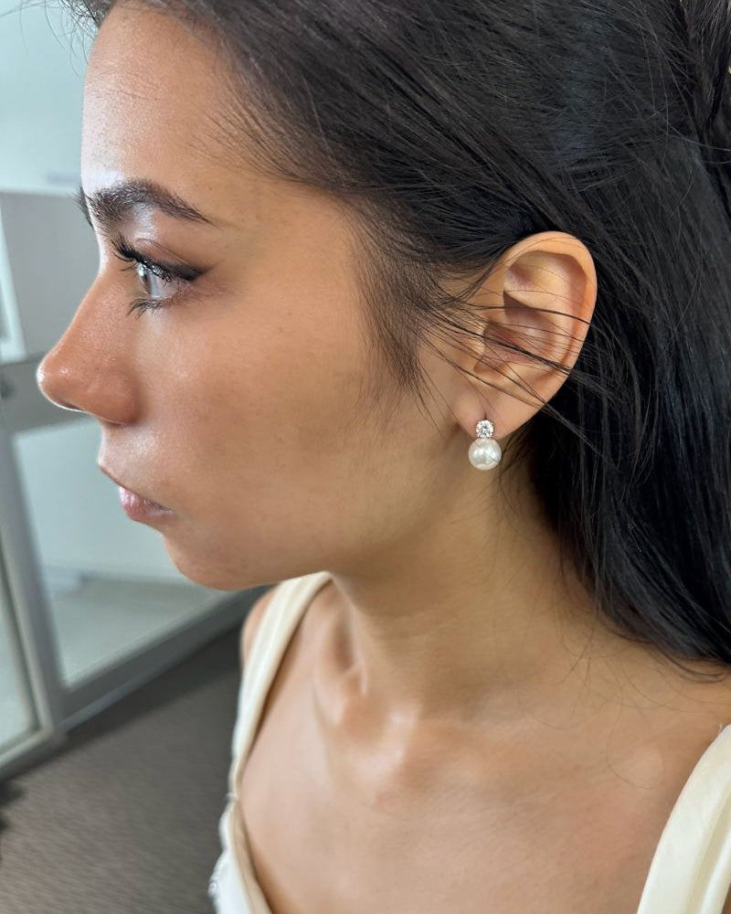 Close-up of a woman wearing pearl earrings in an indoor setting