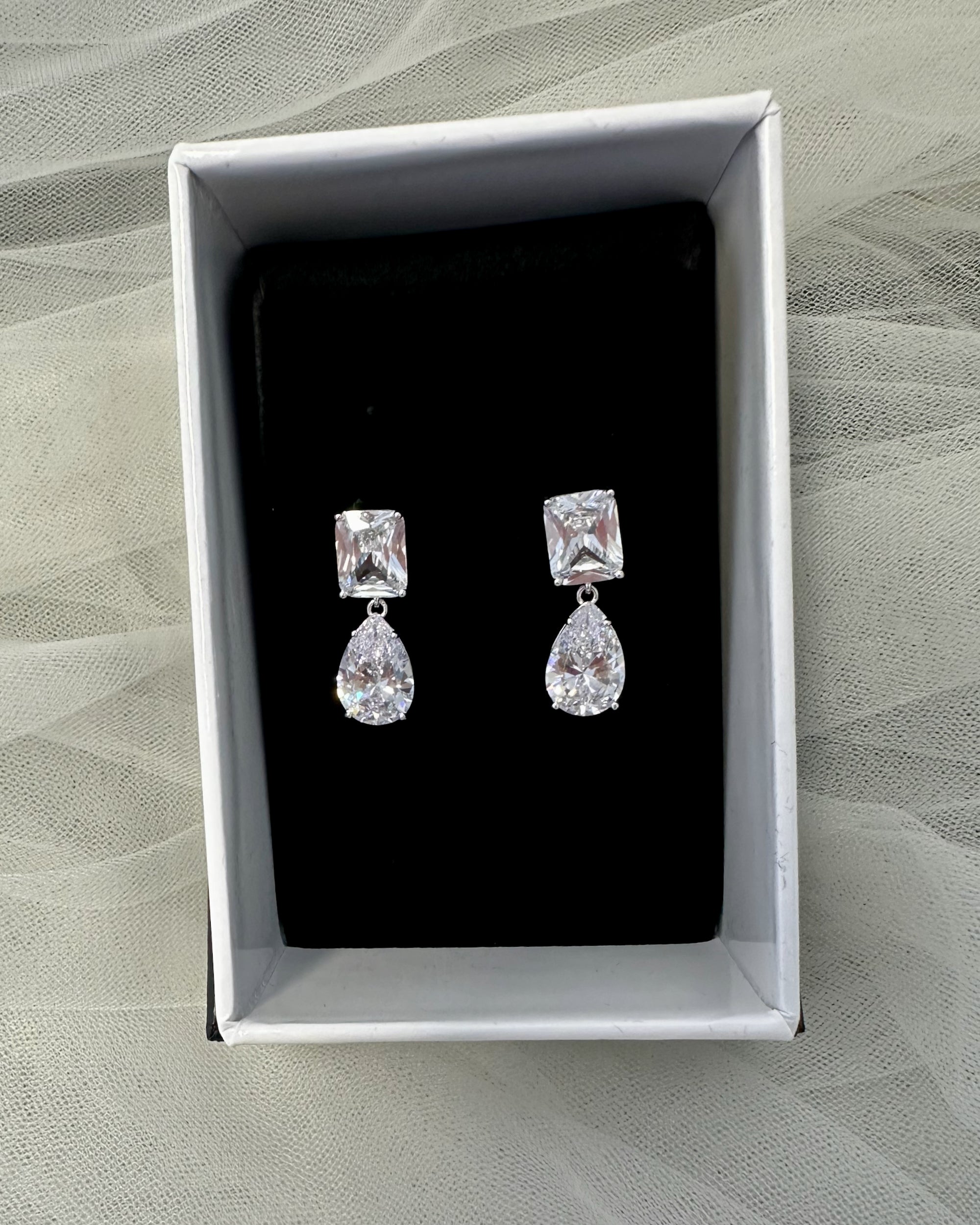 Pair of earrings in a white box on a textured surface