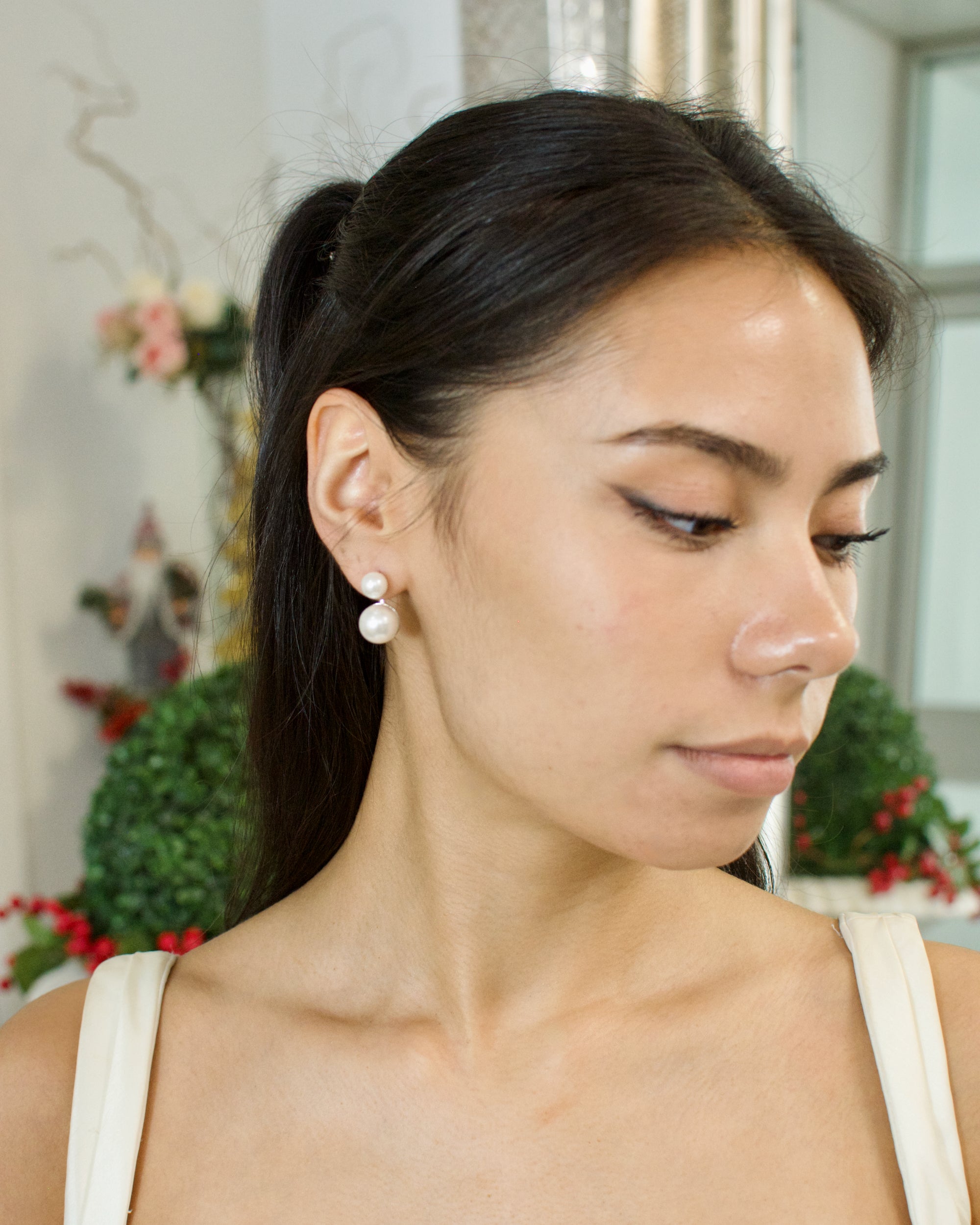 Woman wearing a white earring in a blurred indoor setting