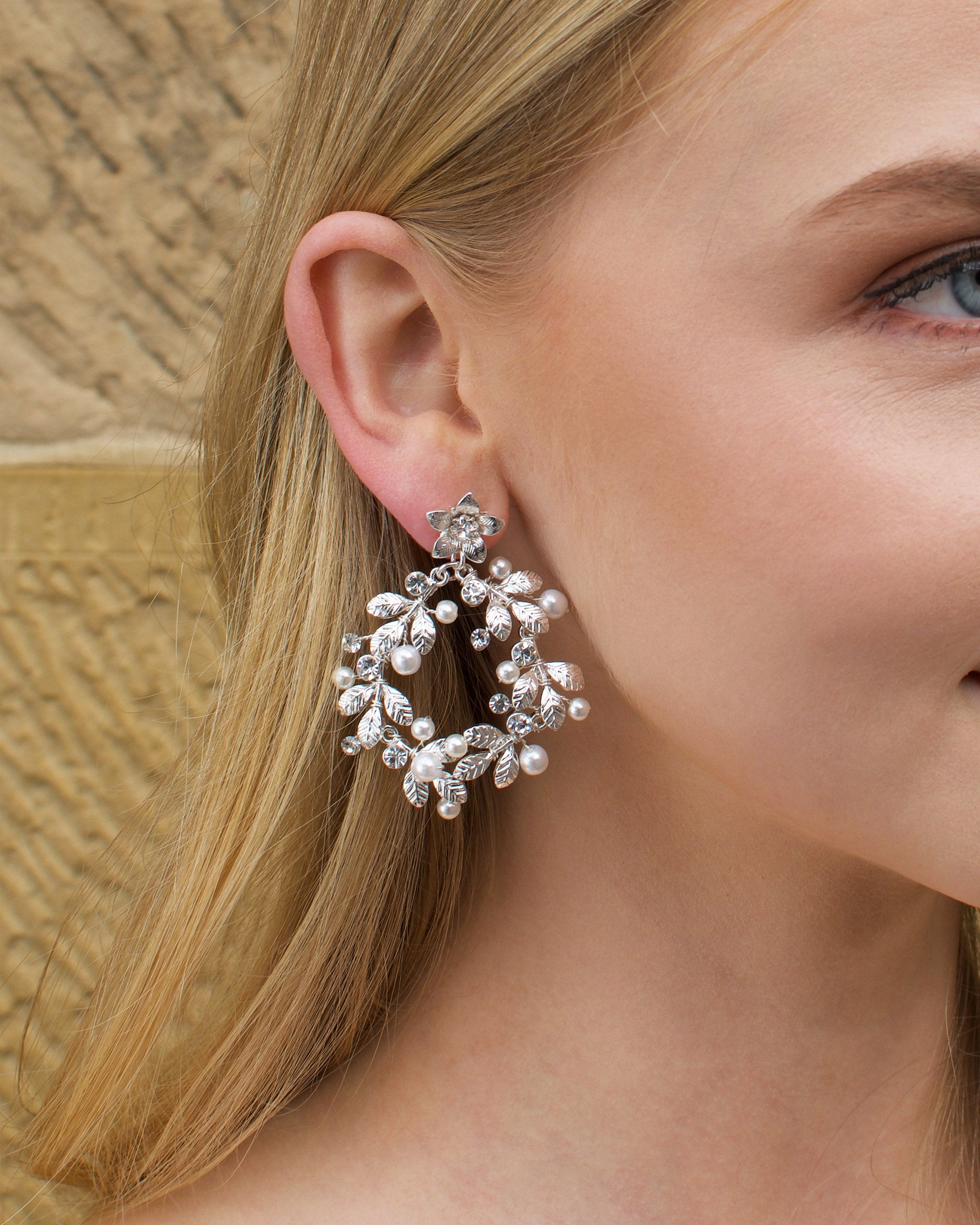Model with Blonde hair wears a silver hoop shape earring in her ear.