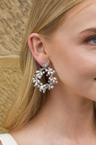 Model with Blonde hair wears a silver hoop shape earring in her ear.