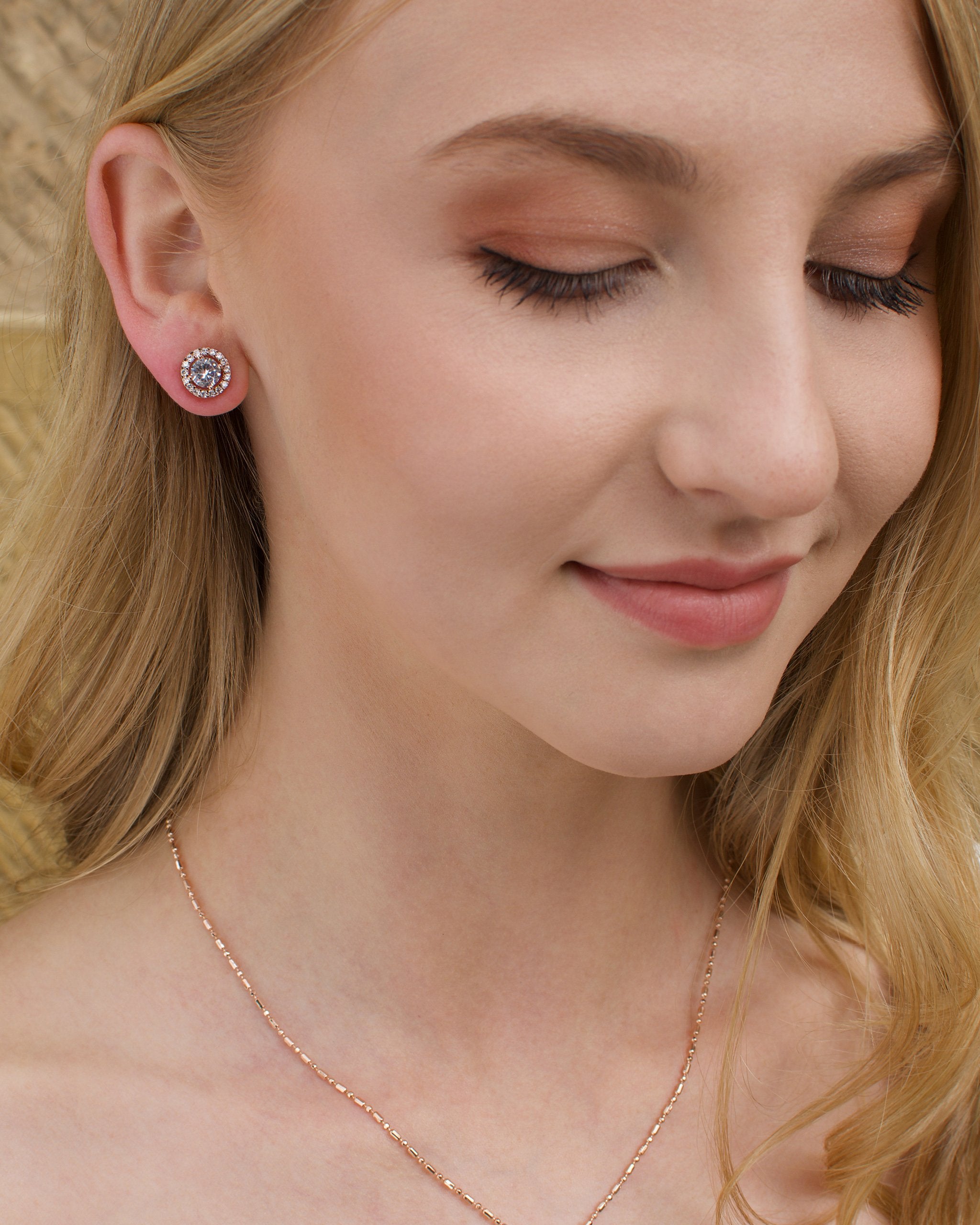 Close up of a model wearing a rose gold stud earring and a rose gold simple pendant