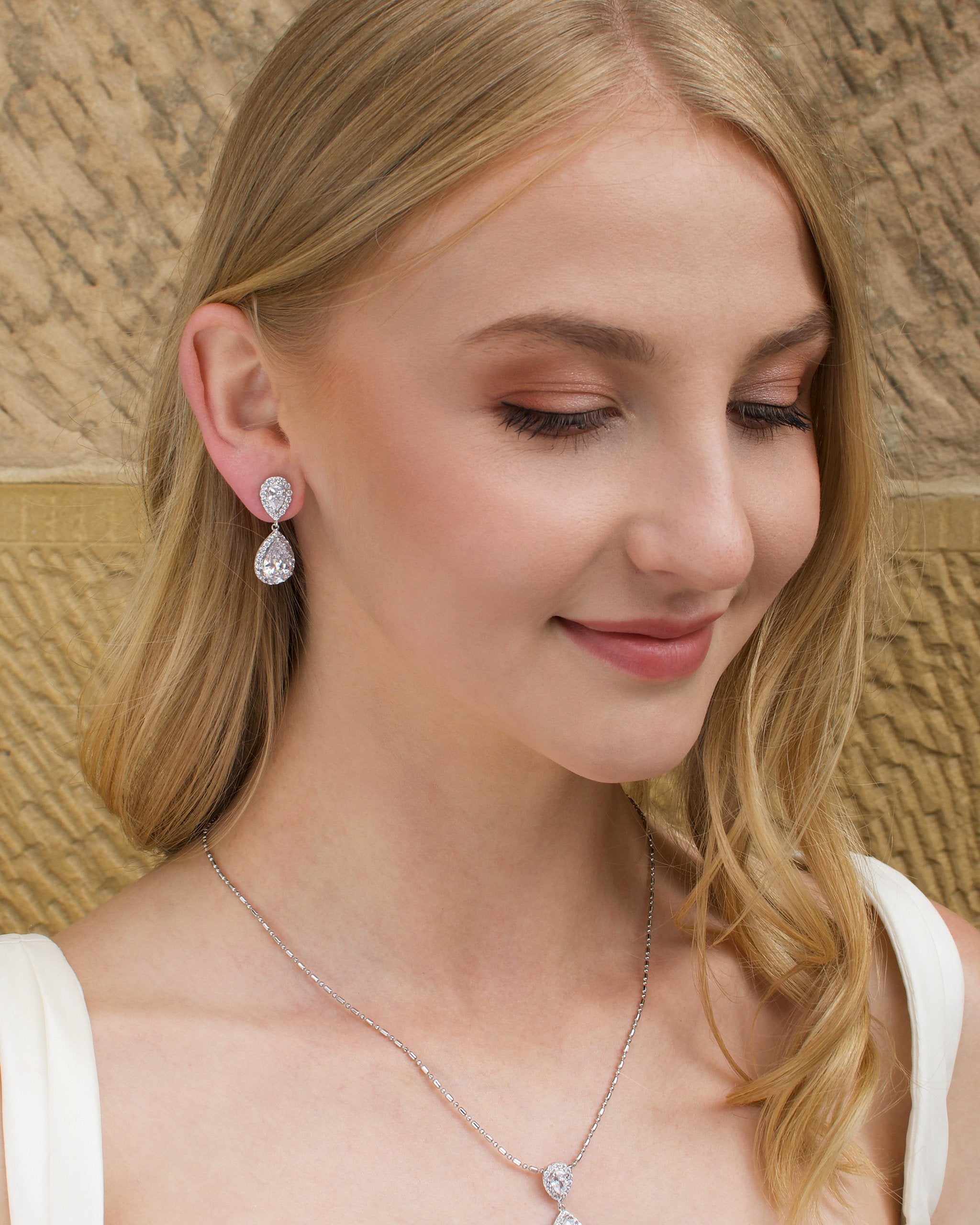 Blonde Bridal Model wearing a short pear shape drop earring with a sandstone backdrop