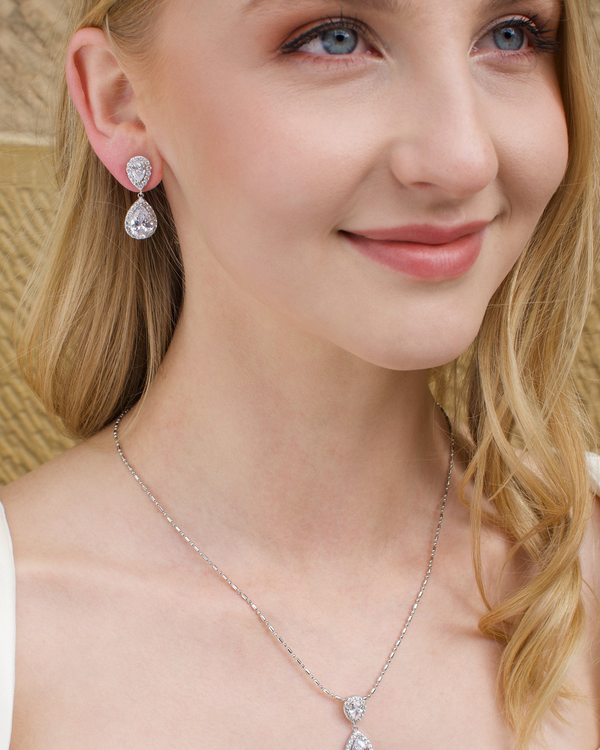 Blonde Model earring a matching pear shape earring and pendant necklace with a sandstone backdrop