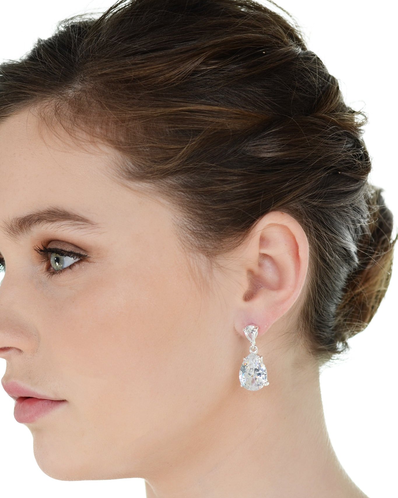 Dark haired model wearing a pear shaped stone earring against a white background.