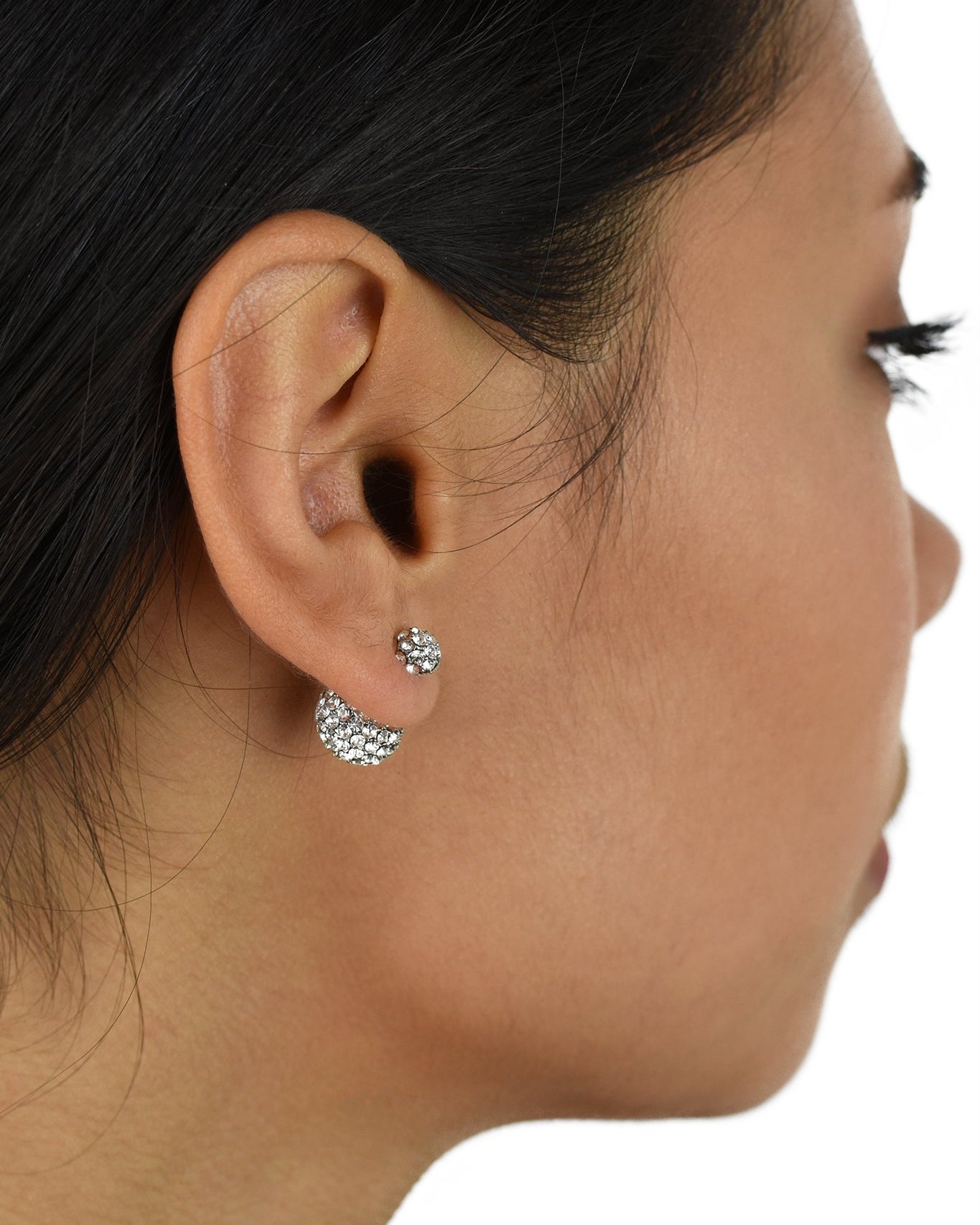 The ear of a dark hair model shows a large crystal ball at the back of the ear with a small crystal ball on the front of the ear.