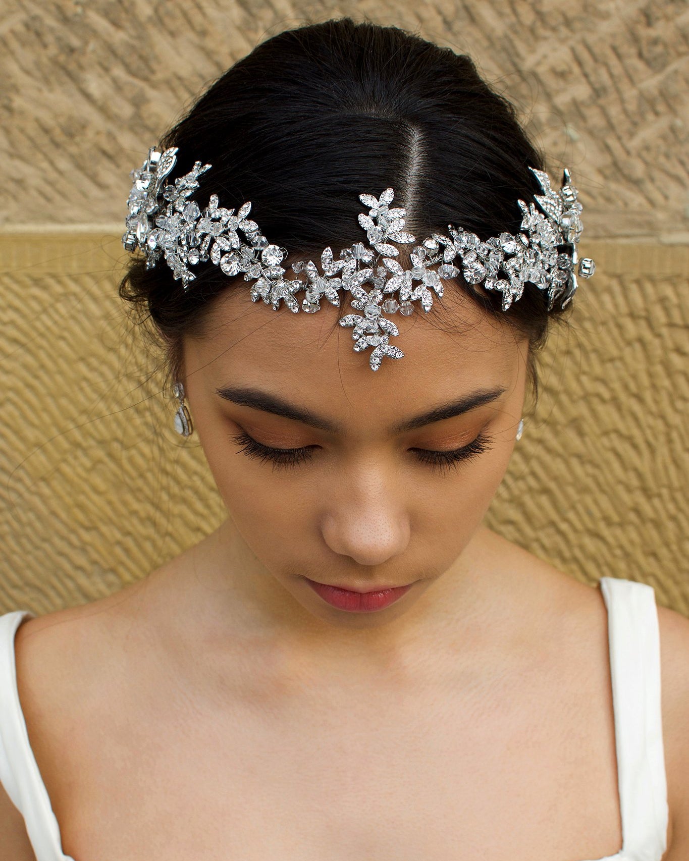 Long Bridal Vine in Dark Silver and crystal worn on the front of a Brides head in front of a stone wall