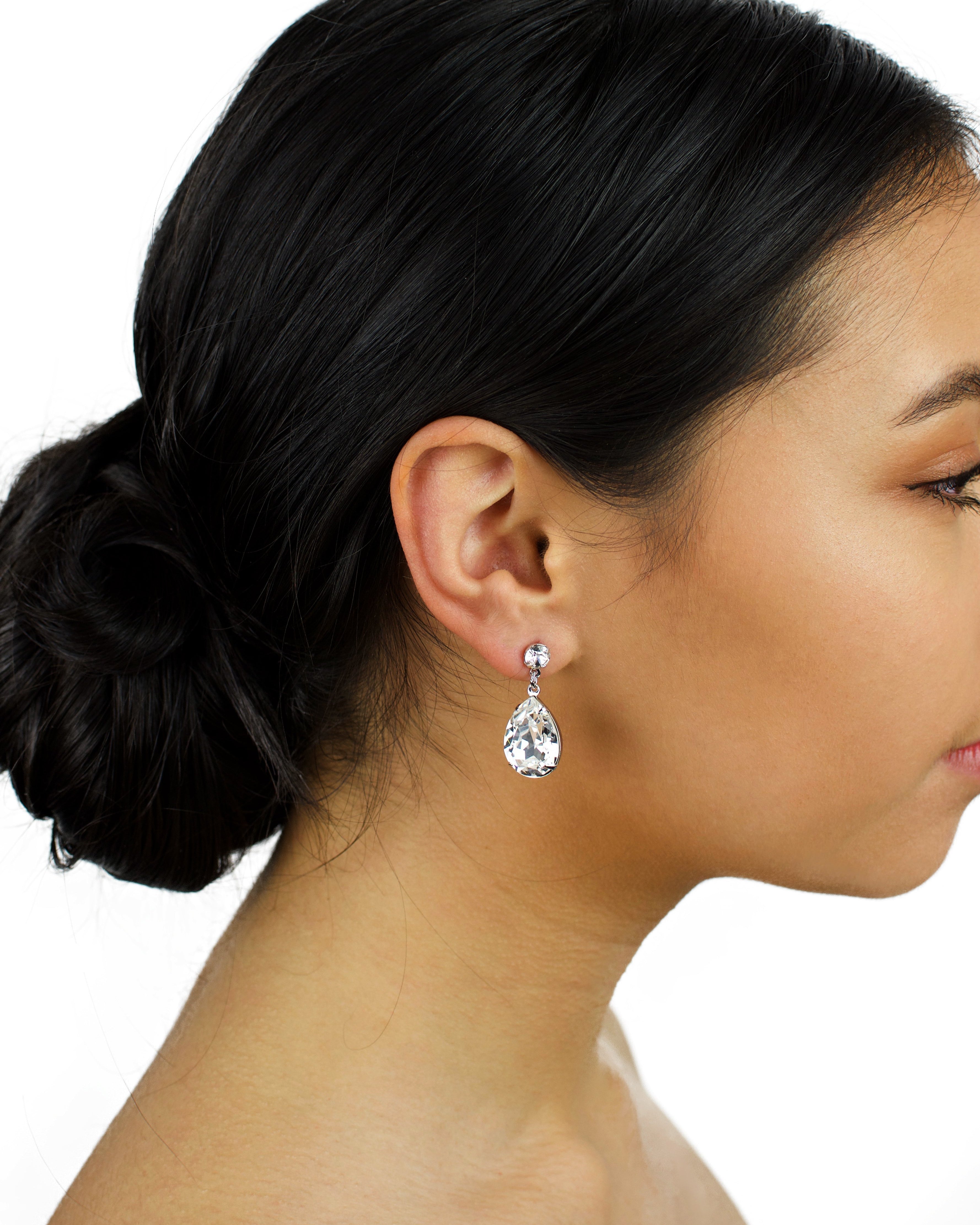Dark haired model wears a silver earring with a clear Swarovski stone