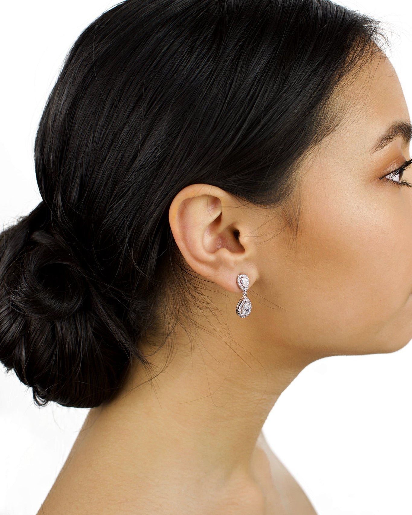 Small Silver pear shape earring worn by a bride with dark hair on a white background