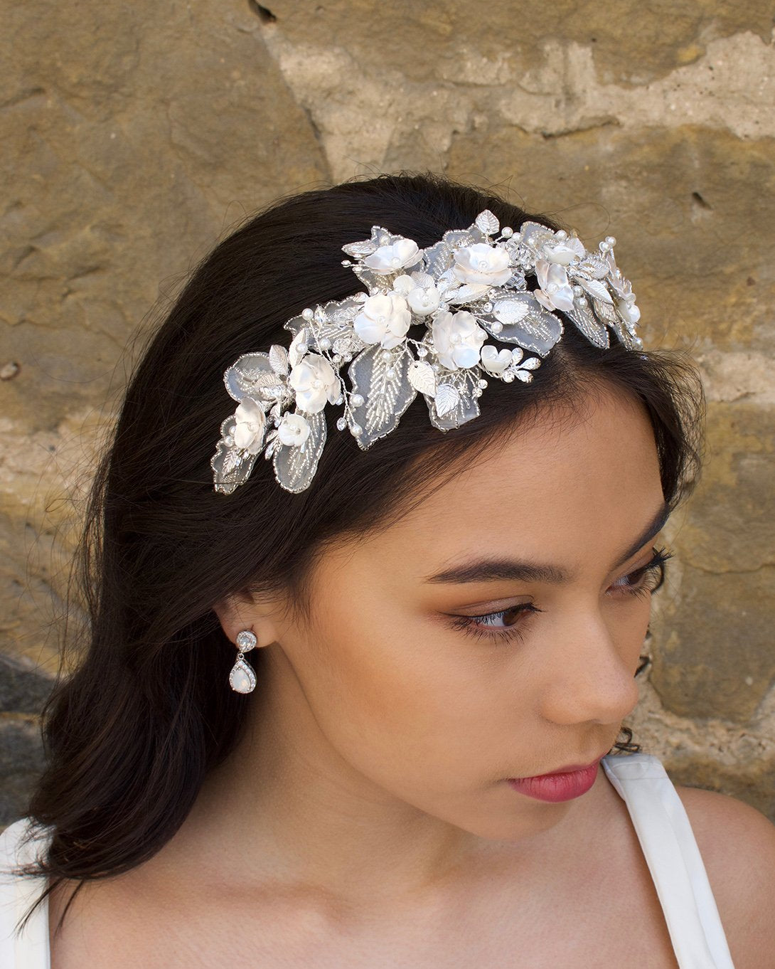 Black hair Bride wearing a lace and flower headband in front of a stone wall