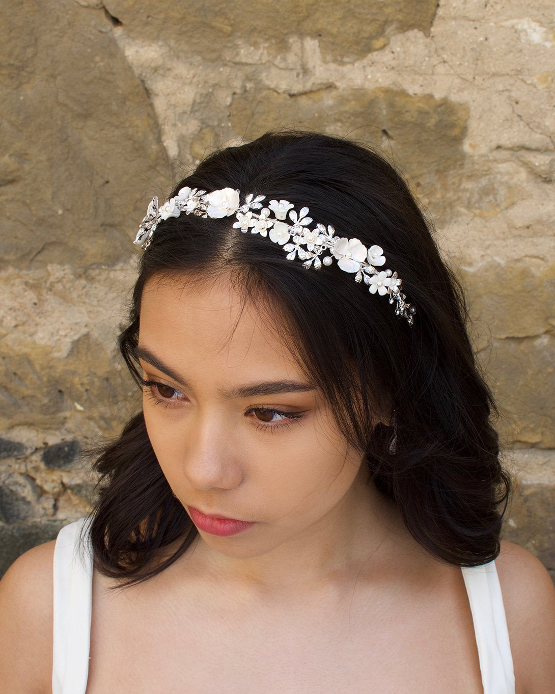 Black haired Bride wearing a White and Silver Flowers headband with a stone wall background