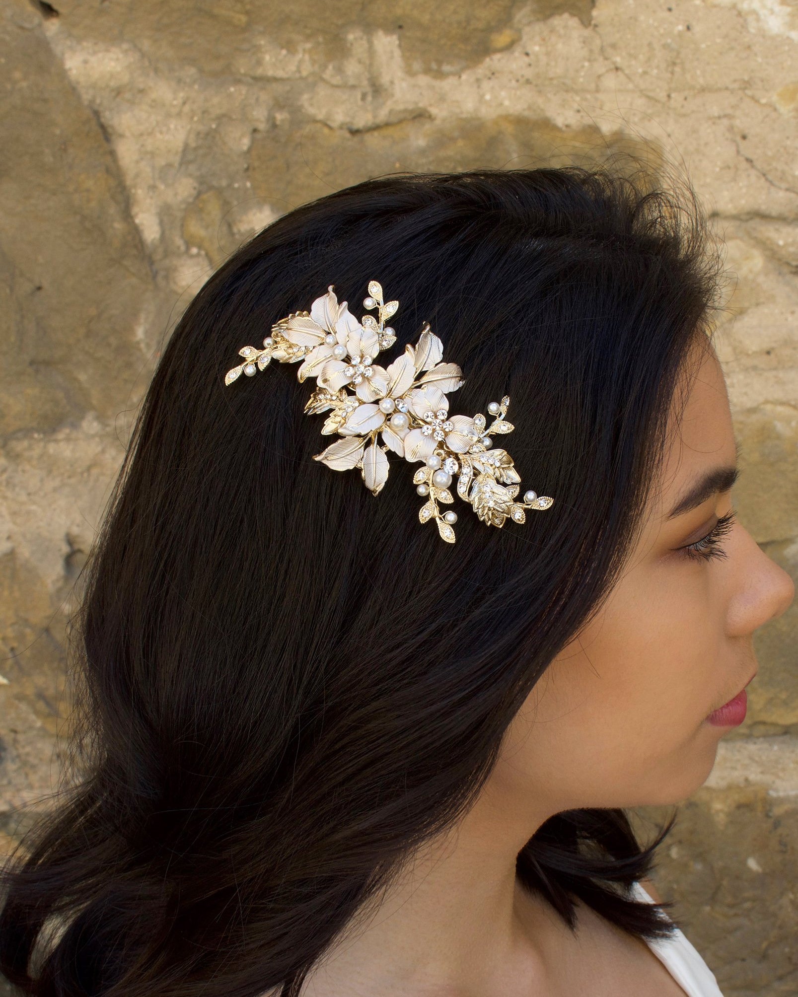 Pale Gold and peal side comb worn by a dark haired bride with a stone wall backdrop