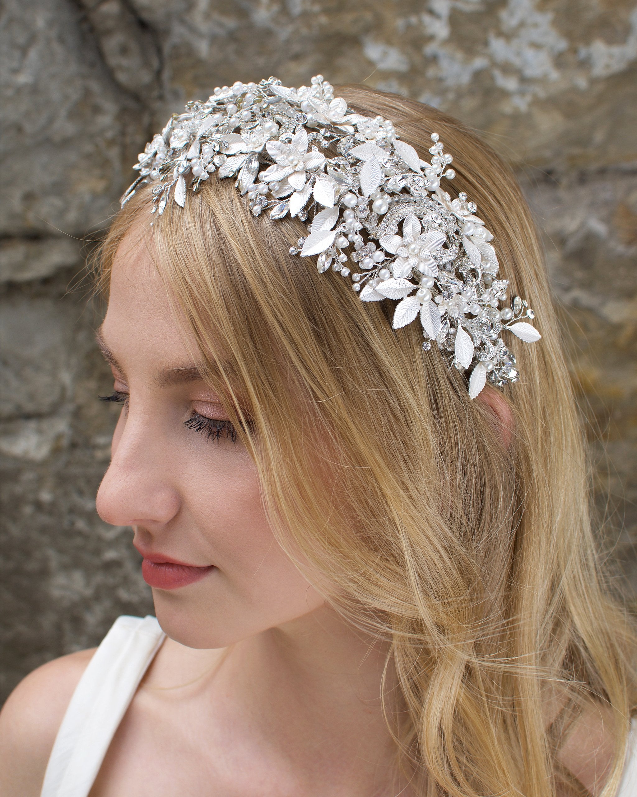 A bride with blonde hair wears a wide silver flowers headband with leaves