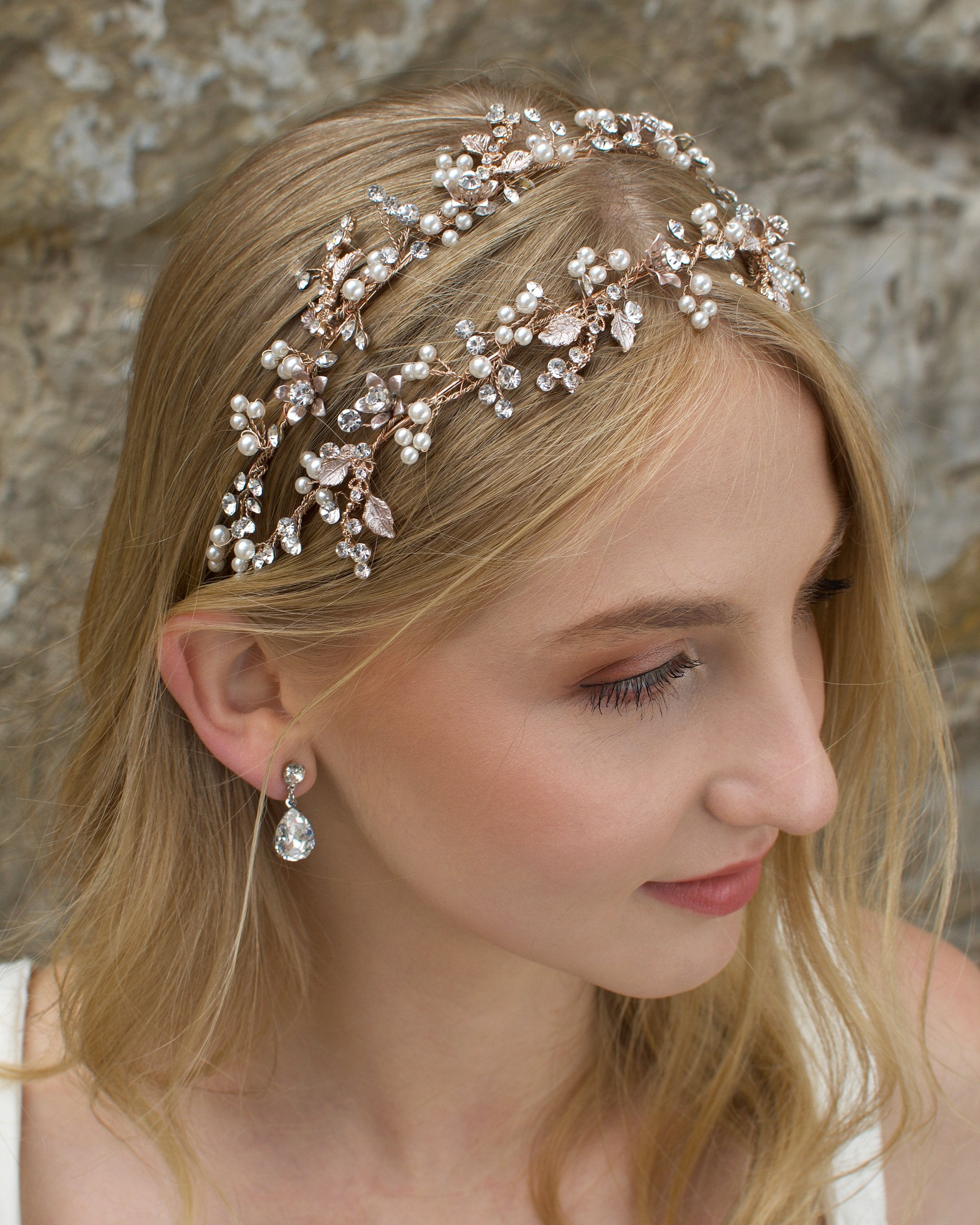 Double row headband in rose gold worn by a blonde model with a stone wall background