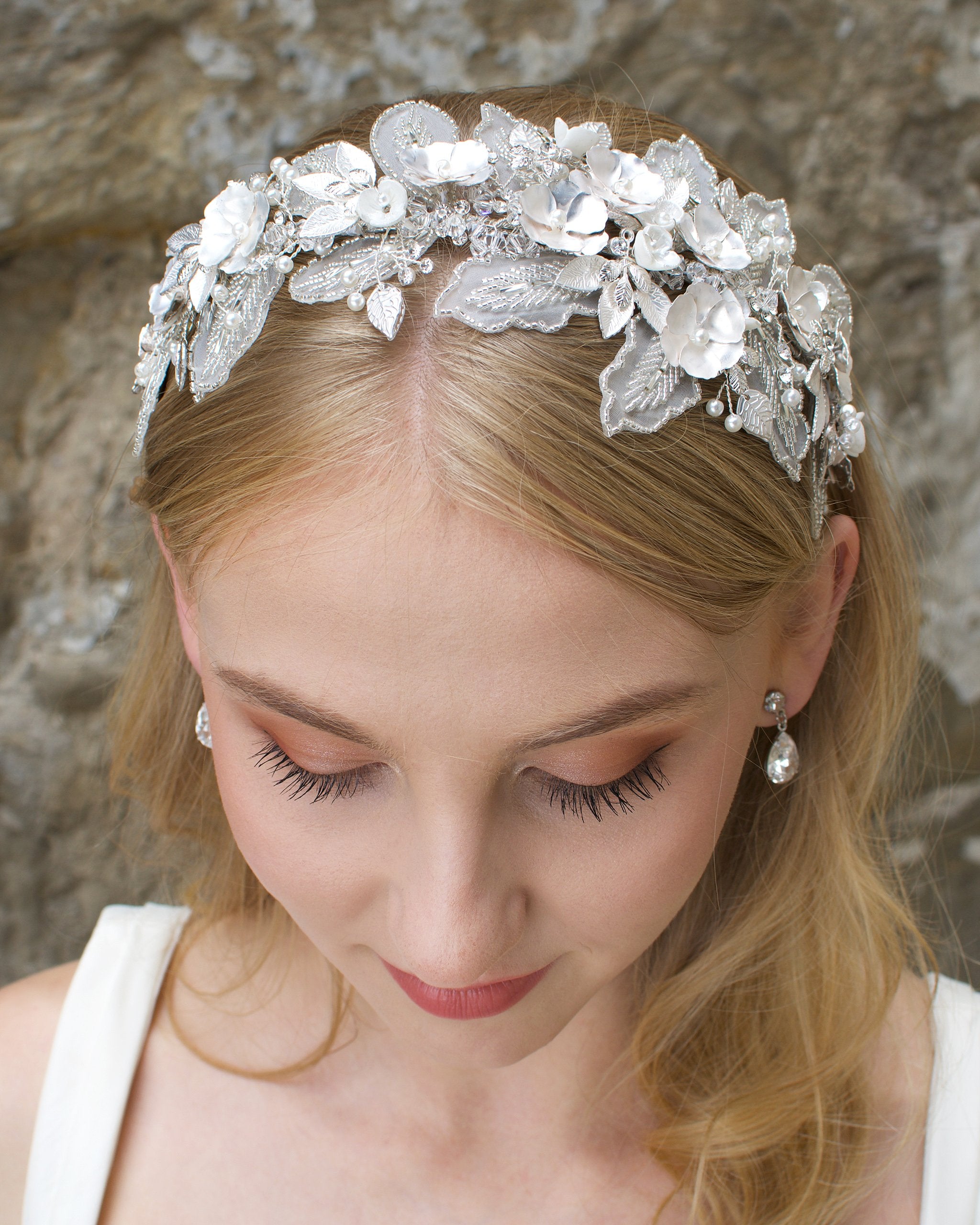 Lace Headband with white flowers worn by a blonde bride with a wall backdrop