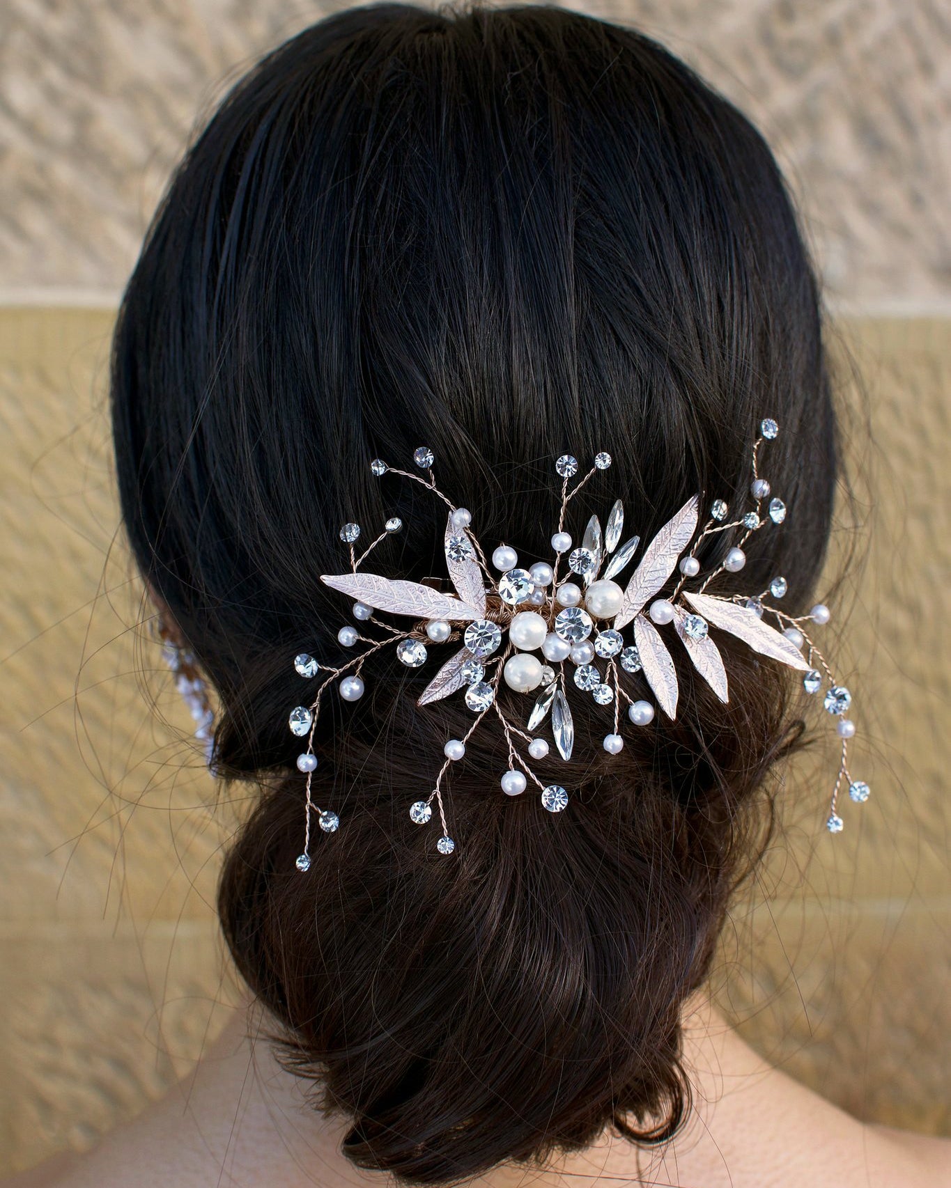 dark hair model wears a comb with pearls and leaves at the back of her head