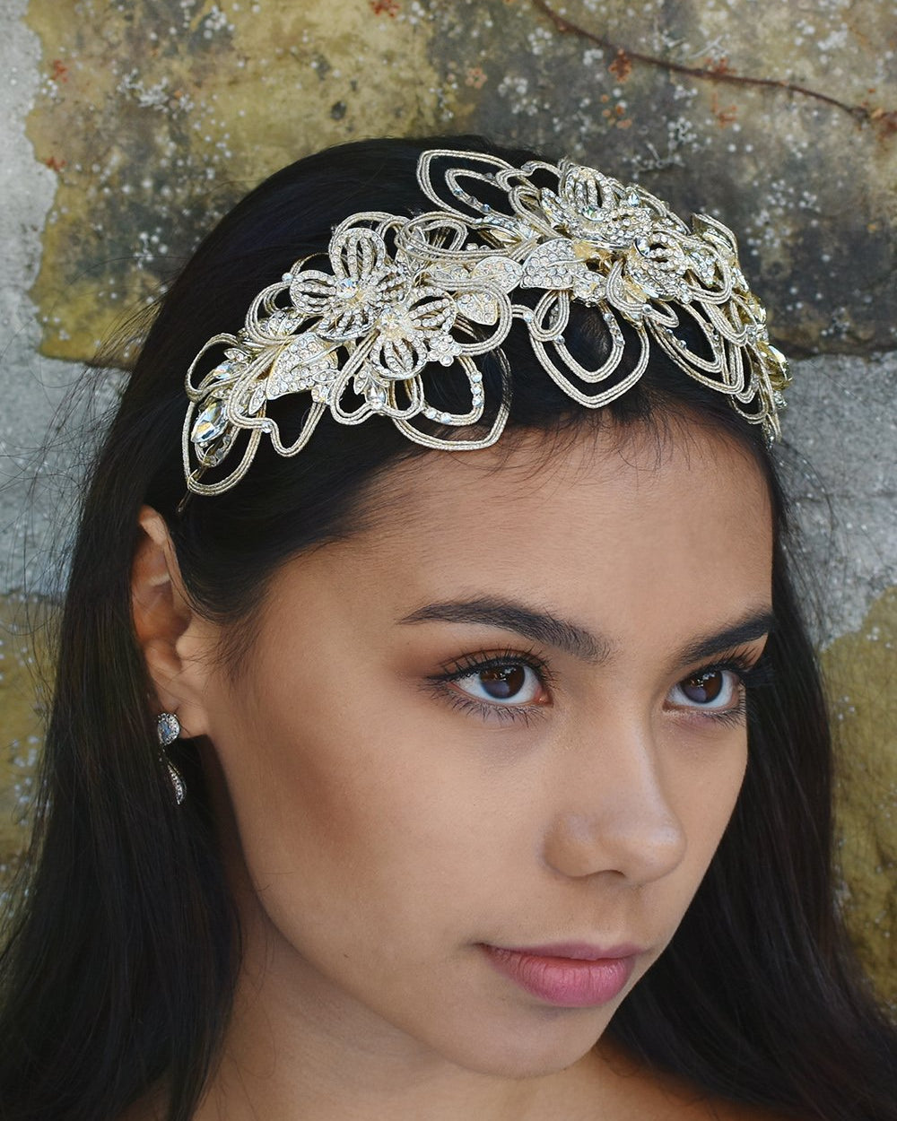 Matt Gold Bridal Headpiece worn by a dark hair model with a stone wall behind her.