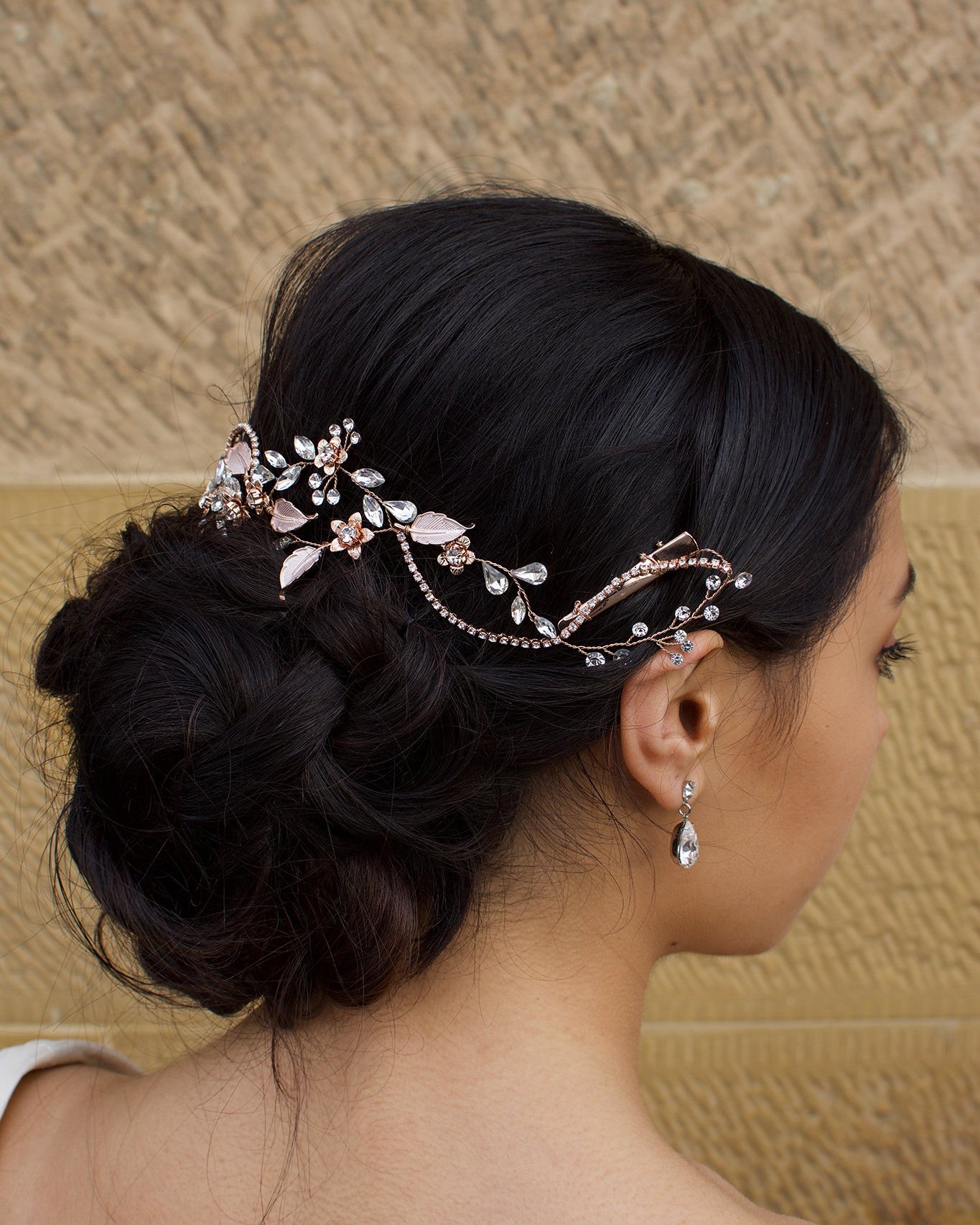 Side view of a Bridal Model with Pale Rose Gold Hair Vine with a stone background