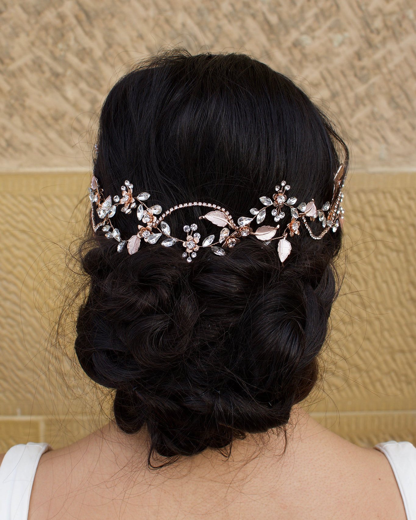 Pale Rose Gold Bridal Hair Vine on Dark Hair Model with a stone wall background