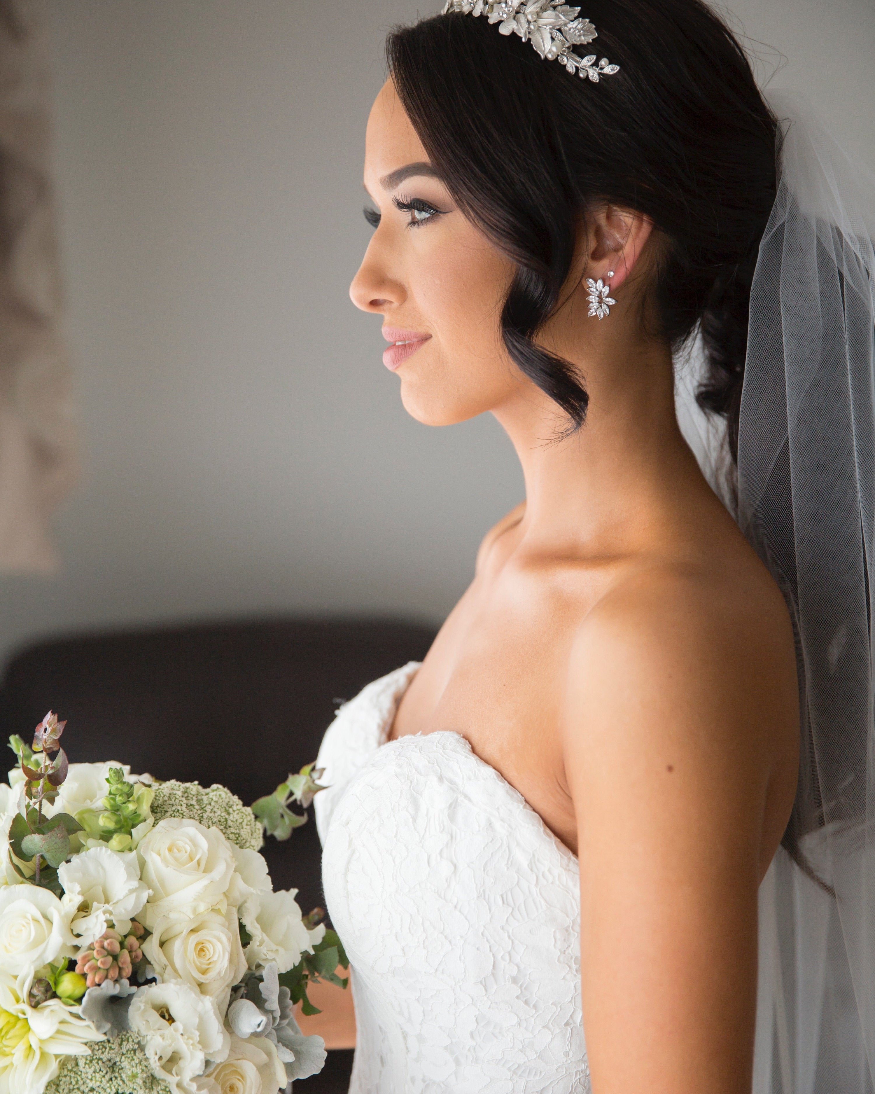 side view of a real bride wearing a silver leaf tiara holding a bouquet of flowers