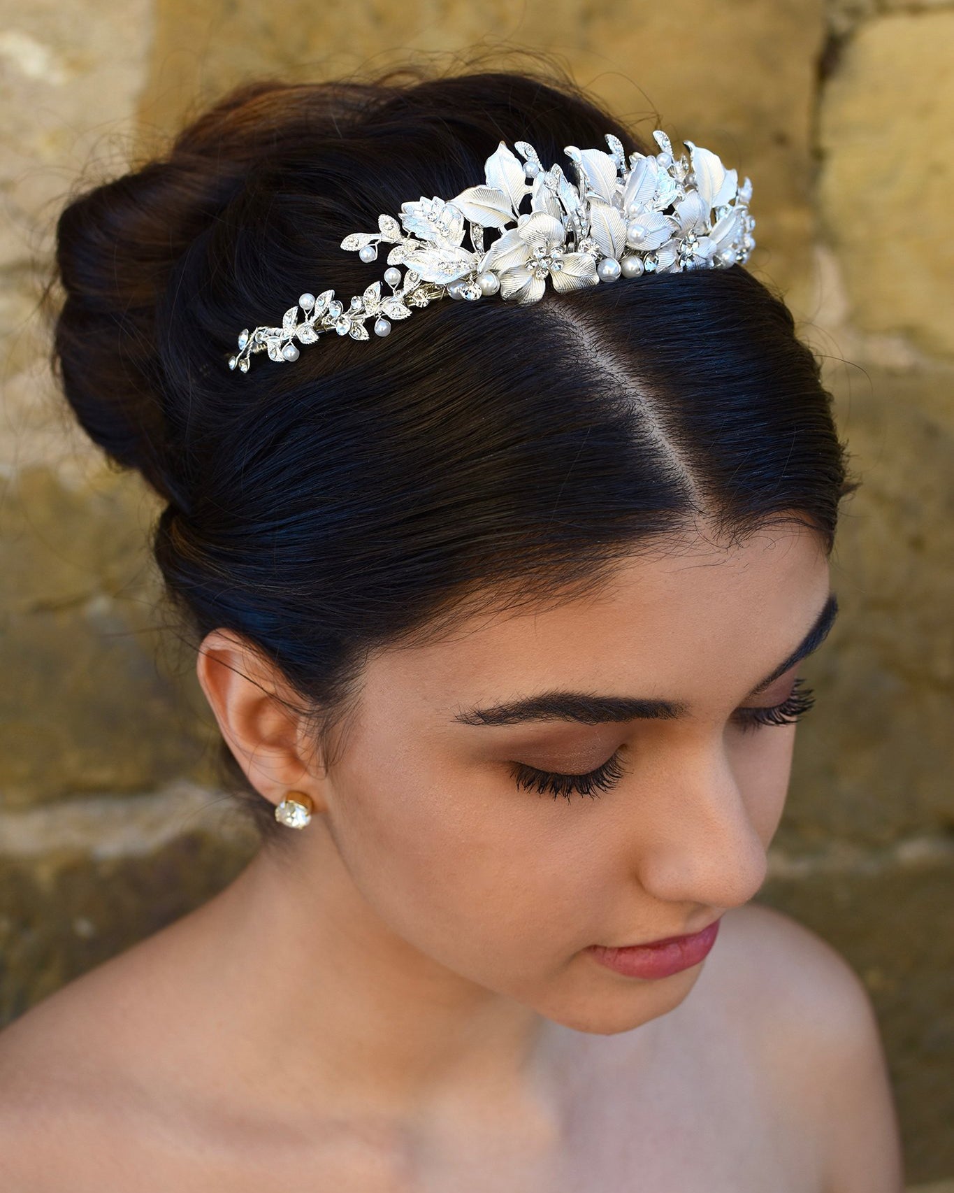 Dark haired bride wears a low silver tiara with a stone wall background