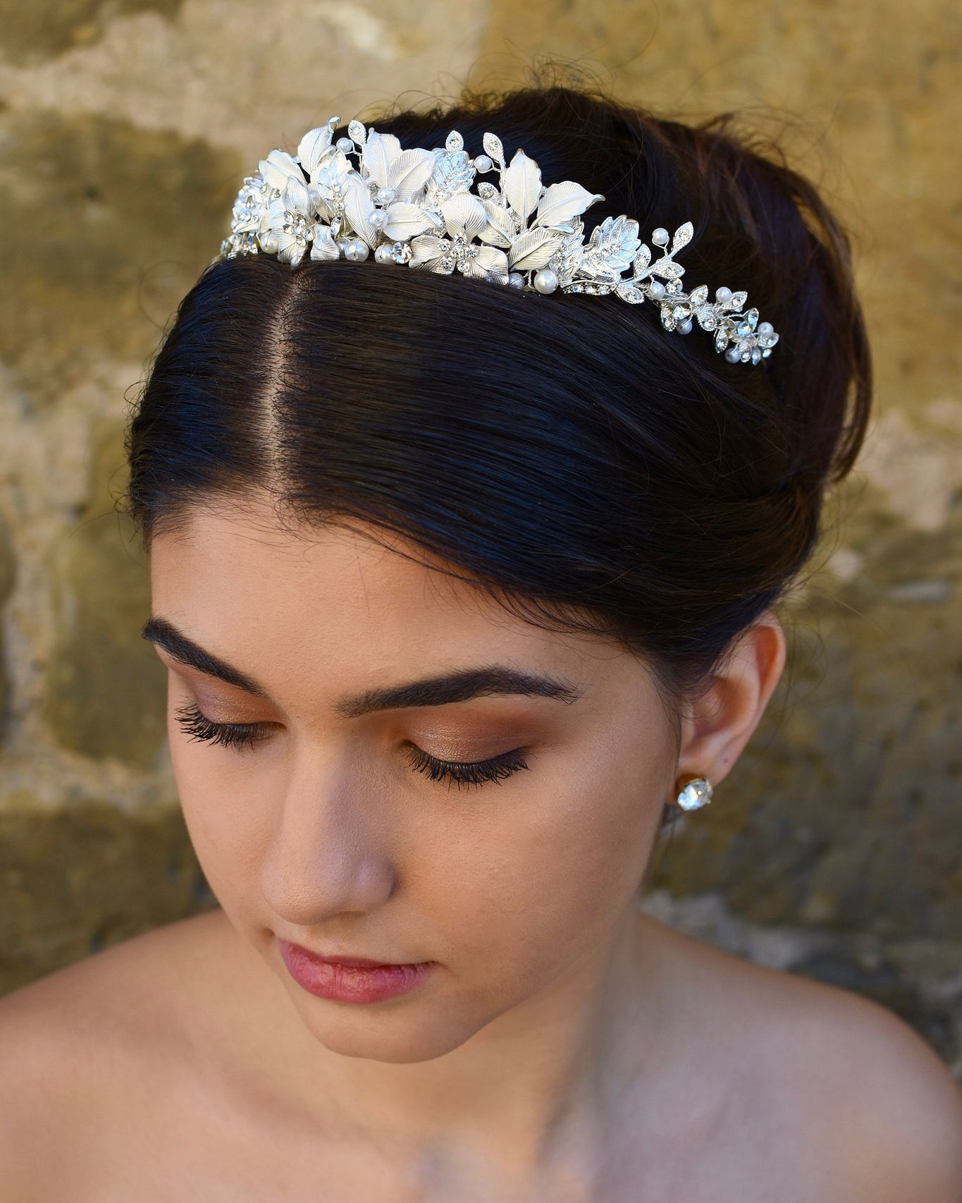 Dark haired bride wears a low silver tiara with a stone wall backdrop