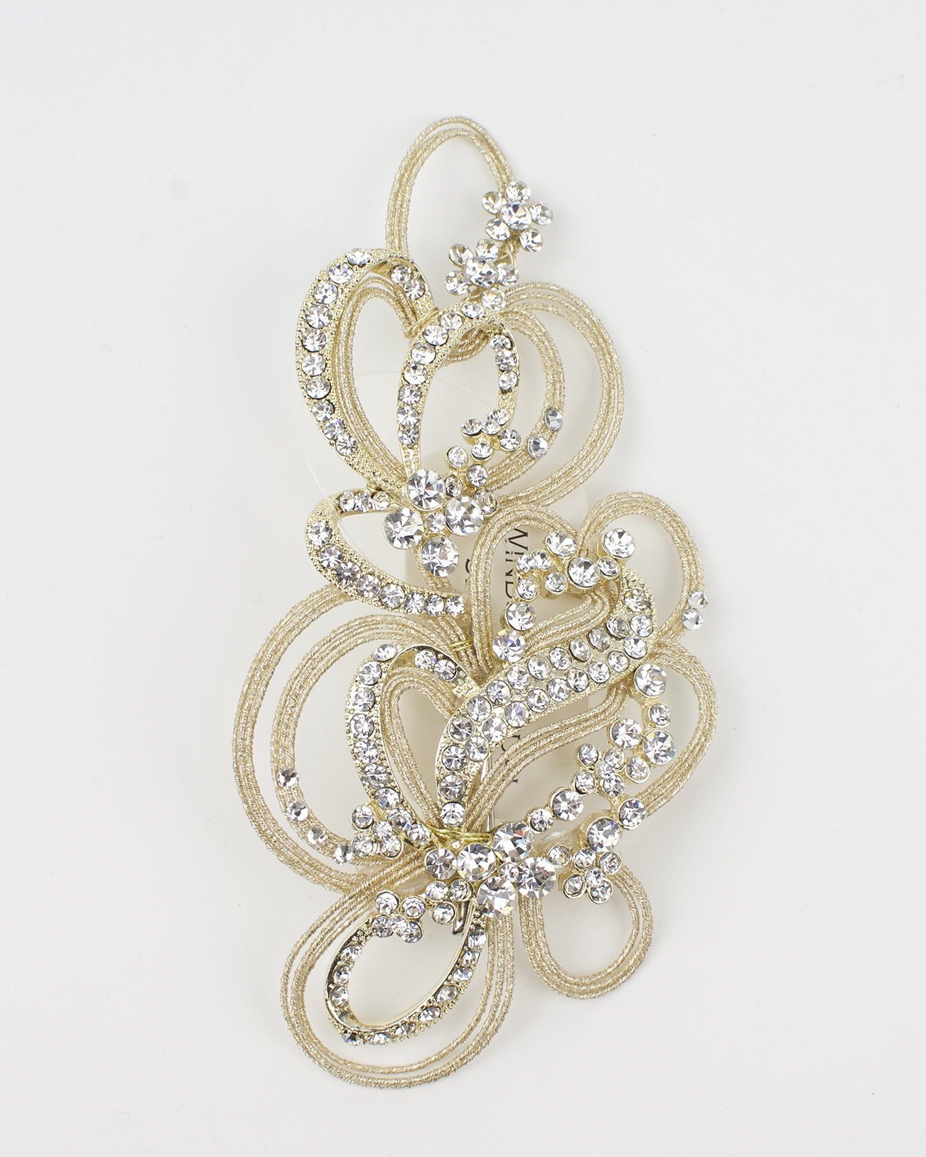A champagne gold bridal comb with many tiny crystals sits on a pure white background
