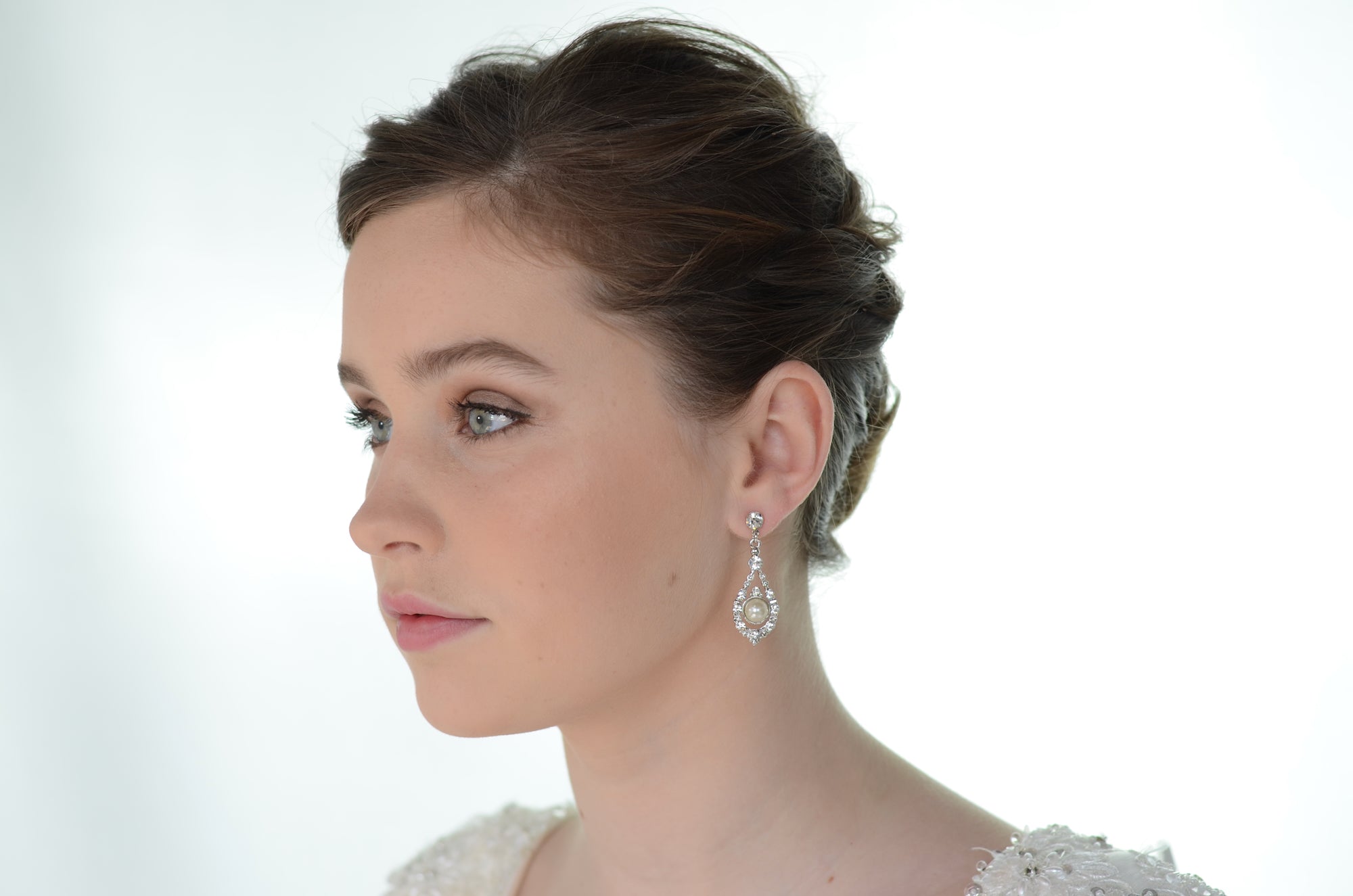 Close-up of a woman wearing a diamond earring on a white background
