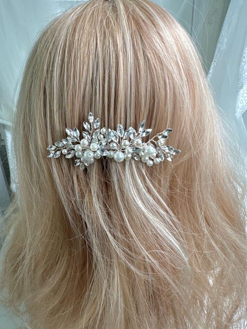 Silver hair comb with pearls in blonde hair against a white background