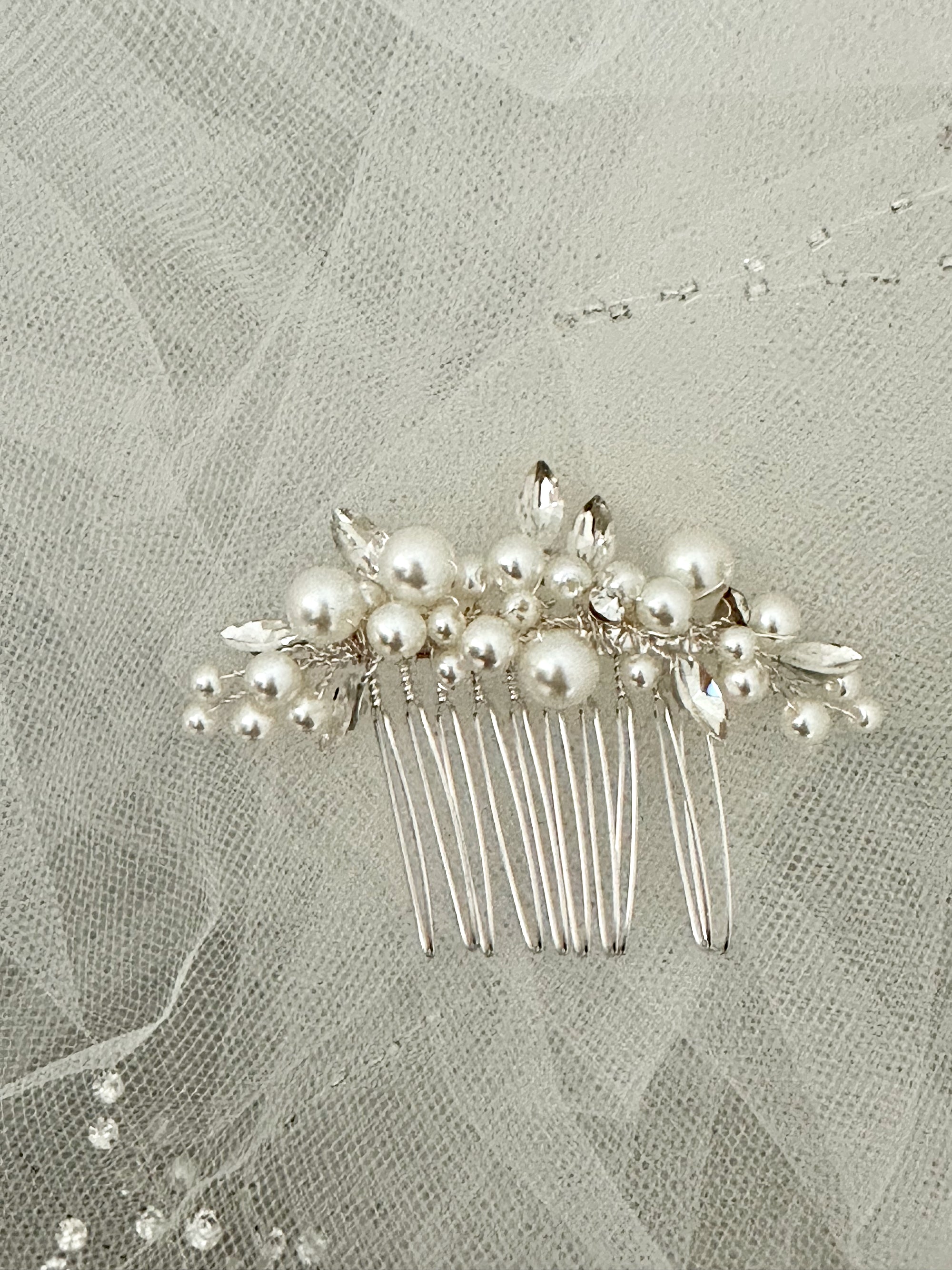 Silver hair comb with pearls on a light gray background