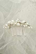 Silver hair comb with pearls on a textured fabric background