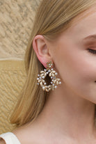 Large hoop shape gold earring worn by a blonde model 