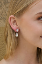 A blonde model bride wears a double teardrop earring with white opal colour stones 