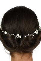 The back of a dark model's head wearing a silver vine with pearls