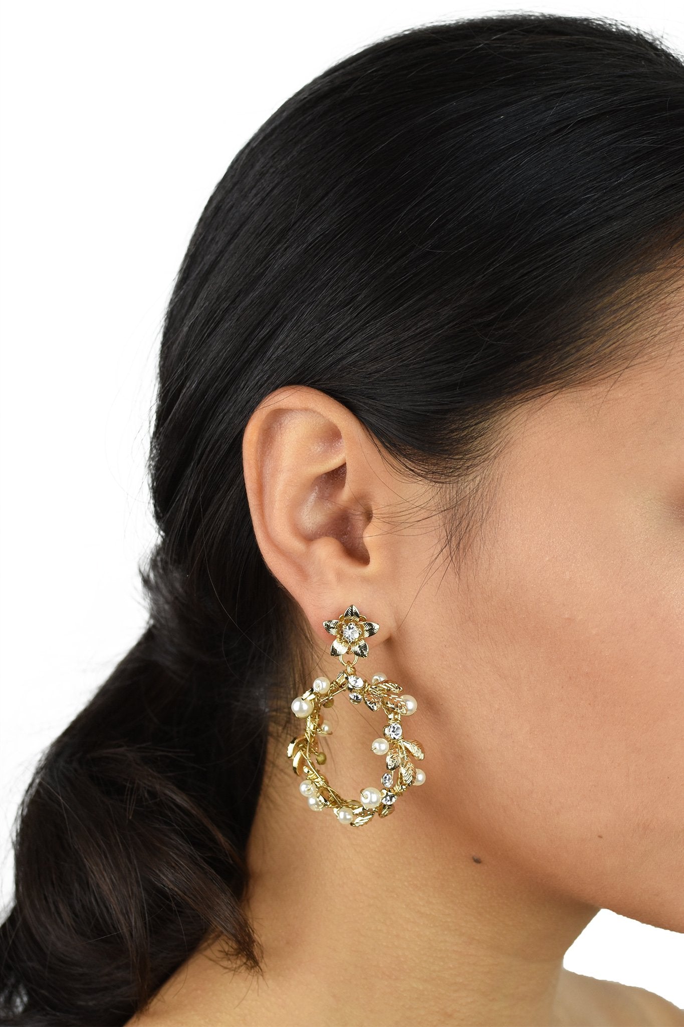 Model wears a gold hoop shape earring. She has dark hair. 