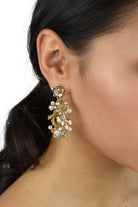 Model wears a gold hoop shape earring in her ear and she has dark hair