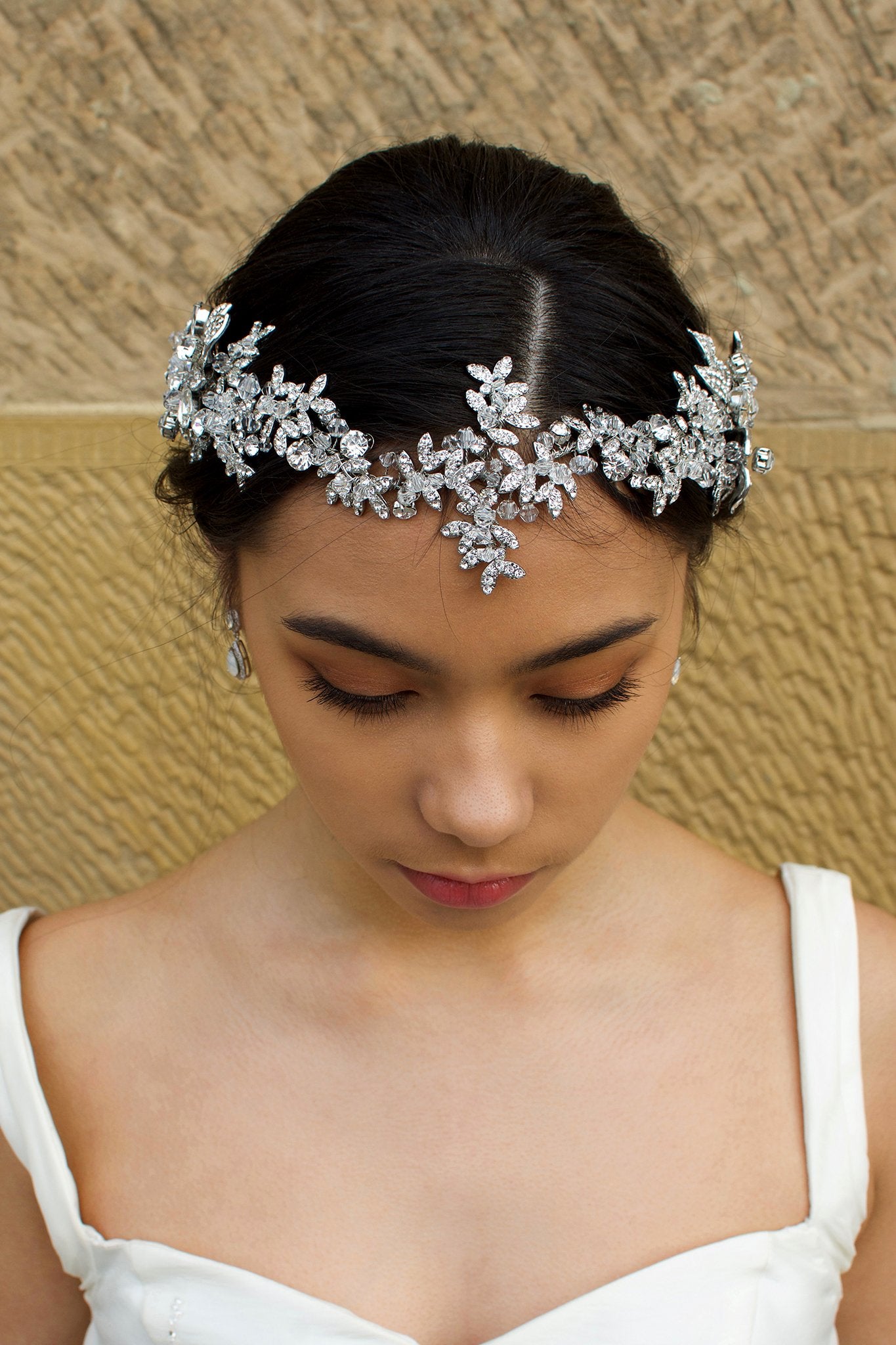 Long Bridal Vine in Dark Silver and crystal worn on the front of a Brides head in front of a stone wall