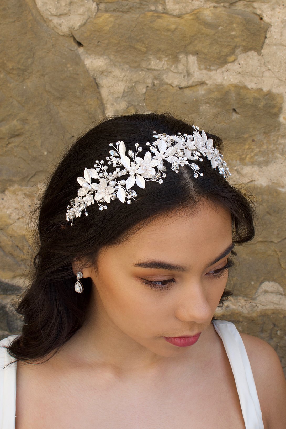 Black haired model wears a silver leaves headband with a wall backdrop