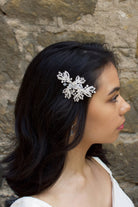 Model with dark hair wears a silver  side comb with a stone wall backdrop