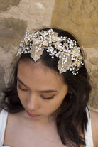 A wide gold headband worn by a dark hair bride with a stone background