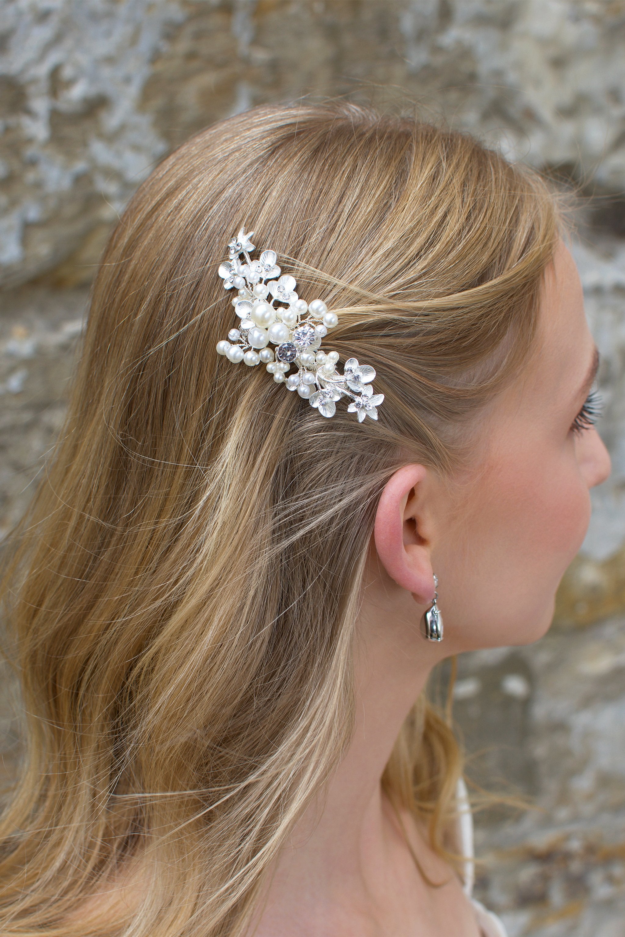 Blonde hair bride wears pearl and silver bridal side comb on the side of her head.