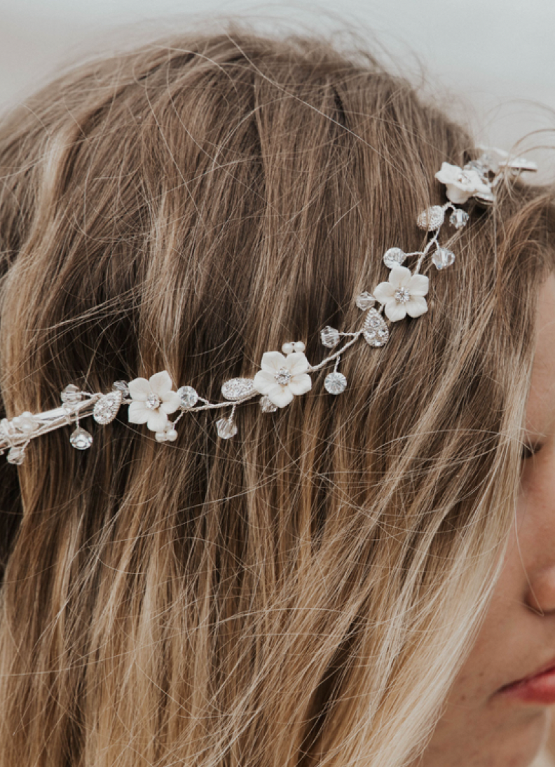 A model with tousled blonde hair wears a flower vine in a bridal hairstyle