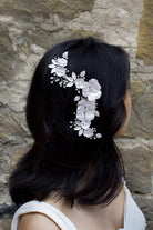 Black haired model wears a white bridal comb in front of a stone wall